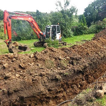 Excavator digging trenches for a ground source heat pump collector